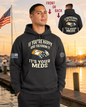 Man wearing a black hoodie with a humorous message by a dock with an American flag.