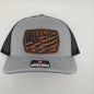 Gray cap with a brown logo and brand tag on a light gray background