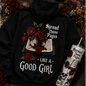 Black hoodie, beige t-shirt, and tumblers with floral and text design on a textured surface.